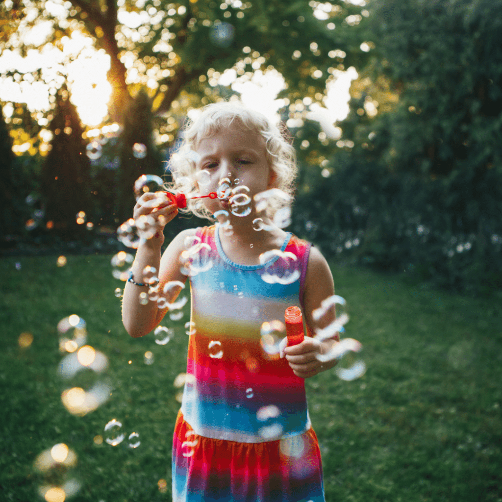 fine motor activites to do outside featured image girl blowing bubbles