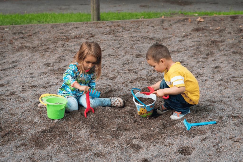 two kids playing in the sand- outdoor activities that promote fine motor skills