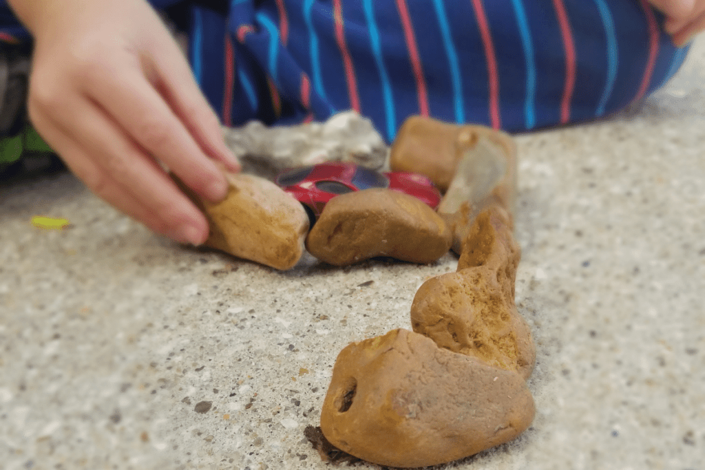 child playing with a car and rocks outside 