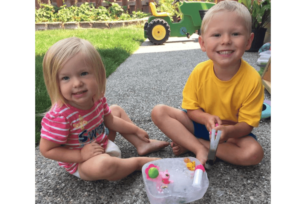 Two kids with a block of ice outside in the summer